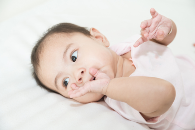 Un bébé avec les doigts dans sa bouche, un signe de faim.