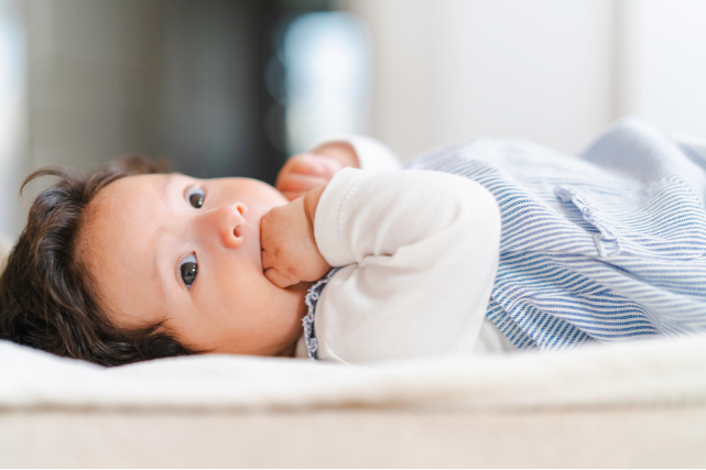 Bébé mettant sa main dans sa bouche